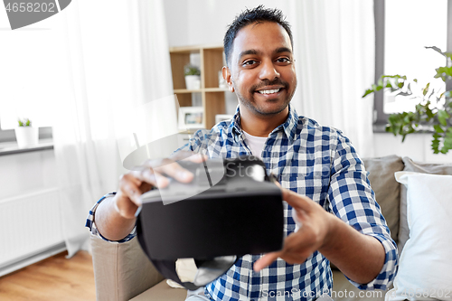 Image of male blogger with vr glasses videoblogging at home