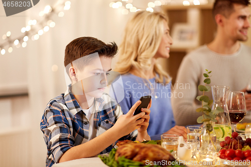 Image of boy with smartphone at family dinner party