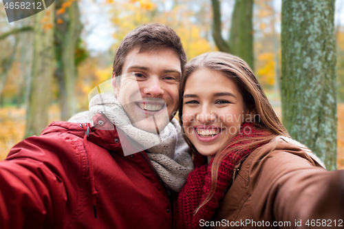 Image of happy young couple taking selfie in autumn park