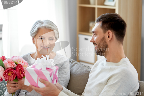 Image of son giving present and flowers to senior mother