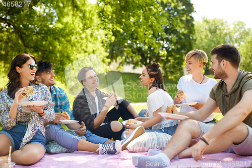 Image of happy friends eating sandwiches at summer picnic