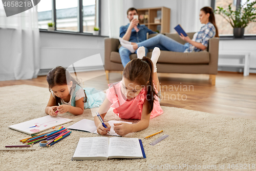 Image of happy sisters drawing and doing homework at home