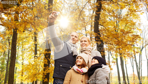 Image of happy family with camera in autumn park