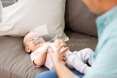 Image of middle aged father playing with baby at home