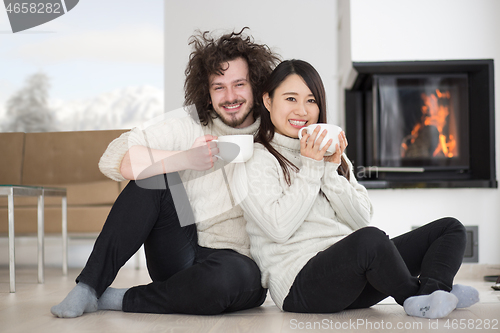 Image of happy multiethnic couple  in front of fireplace