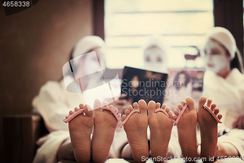 Image of bachelorette party in spa, girls with face mask reading magazine