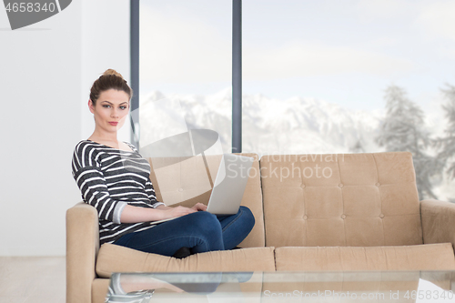 Image of young woman on sofa at home websurfing