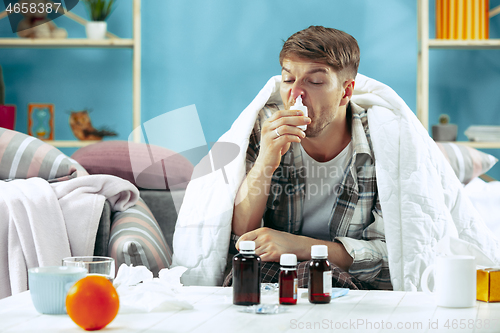 Image of Bearded sick man with flue sitting on sofa at home. Illness, influenza, pain concept. Relaxation at Home. Healthcare Concepts.