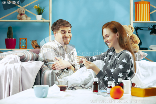 Image of Sick man with fever lying in bed having temperature girl take care for him