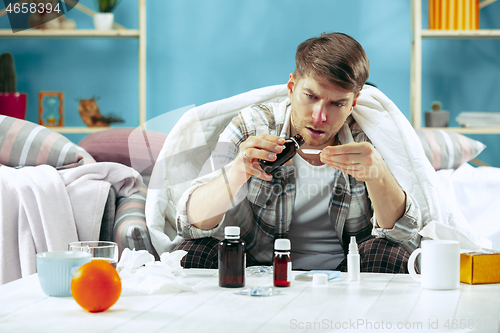 Image of Bearded sick man with flue sitting on sofa at home. Illness, influenza, pain concept. Relaxation at Home. Healthcare Concepts.