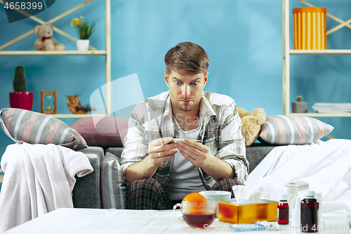 Image of Bearded sick man with flue sitting on sofa at home. Illness, influenza, pain concept. Relaxation at Home. Healthcare Concepts.