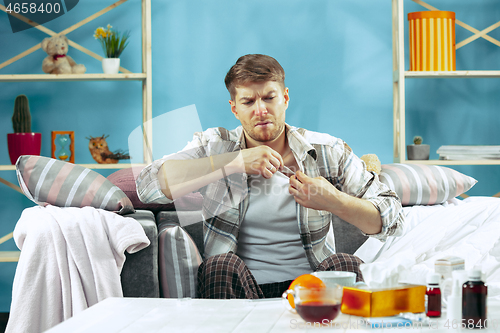 Image of Bearded sick man with flue sitting on sofa at home. Illness, influenza, pain concept. Relaxation at Home. Healthcare Concepts.