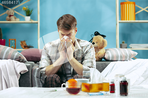 Image of Bearded sick man with flue sitting on sofa at home. Illness, influenza, pain concept. Relaxation at Home. Healthcare Concepts.