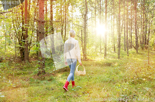 Image of young woman picking mushrooms in autumn forest