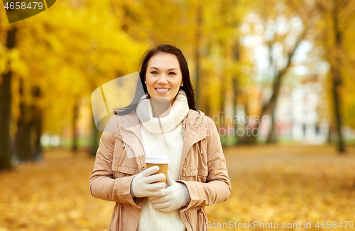 Image of woman drinking takeaway coffee in autumn park