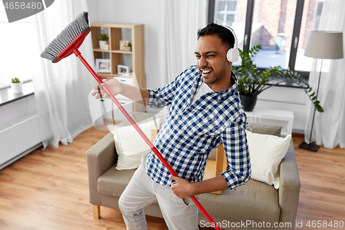 Image of man with broom cleaning and having fun at home