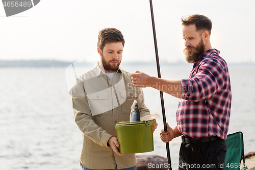 Image of male friends with fish and fishing rods on pier