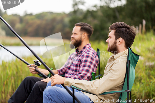 Image of male friends with fishing rods on lake