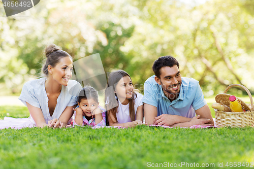 Image of family laying on picnic blanket in summer park