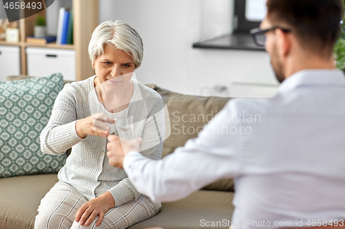 Image of psychologist giving glass of water to senior woman