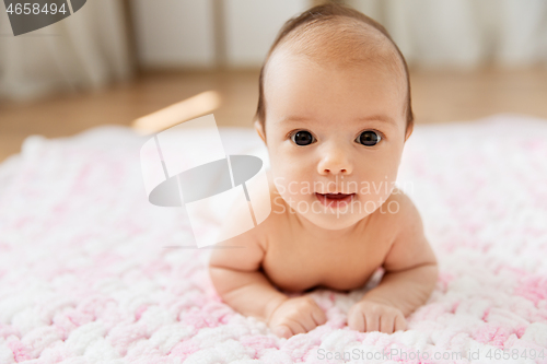 Image of sweet baby girl lying on knitted plush blanket