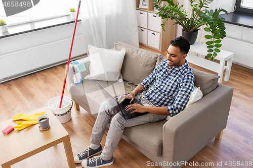 Image of man with laptop computer after home cleaning