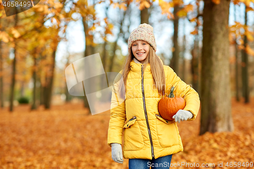 Image of happy girl with pumpkin at autumn park