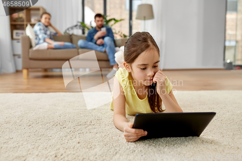 Image of girl with tablet computer lying on floor at home