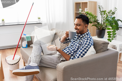 Image of man drinking coffee, resting after home cleaning