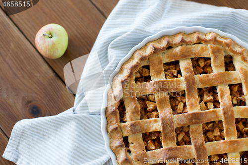 Image of apple pie in baking mold on wooden table