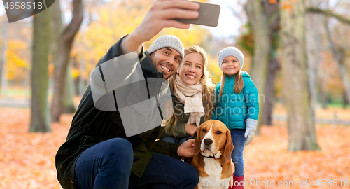 Image of happy family with dog taking selfie in autumn park