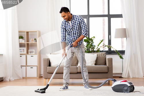 Image of indian man with vacuum cleaner at home