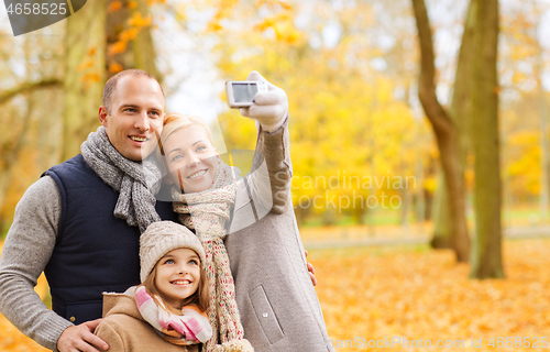 Image of happy family with camera in autumn park