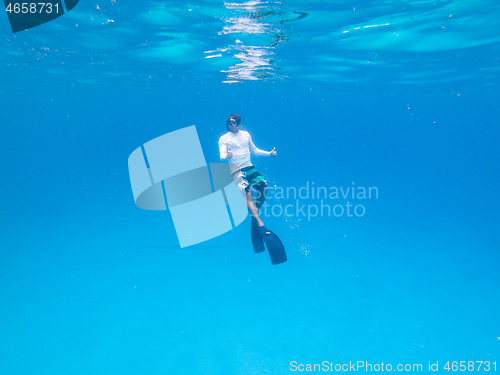 Image of Underwater view of man free diving in blue ocean.