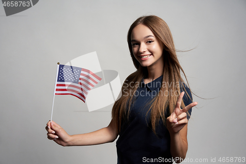 Image of Happy female holding United States of America flag and gesturing Victory