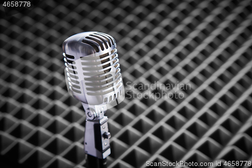 Image of Closeup of chrome retro condenser microphone on acoustic foam panel background