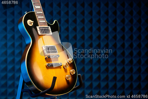 Image of Sunburst electric guitar standing over acoustic foam panel background