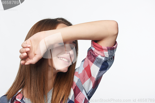 Image of Smiling girl with raised hand shielding eyes