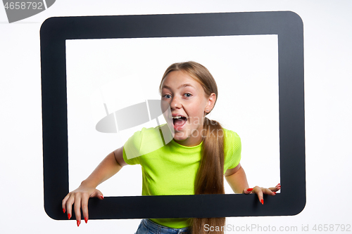 Image of Happy teen girl peeking through digital tablet frame