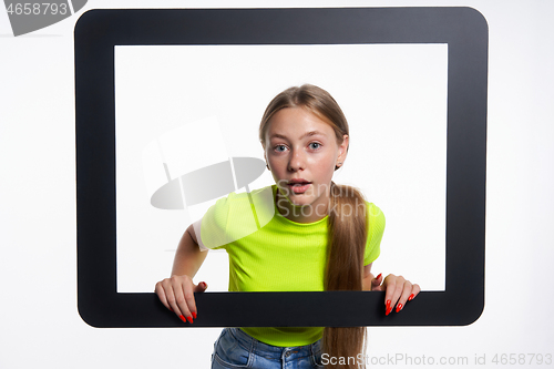 Image of Teen girl peeking through digital tablet frame