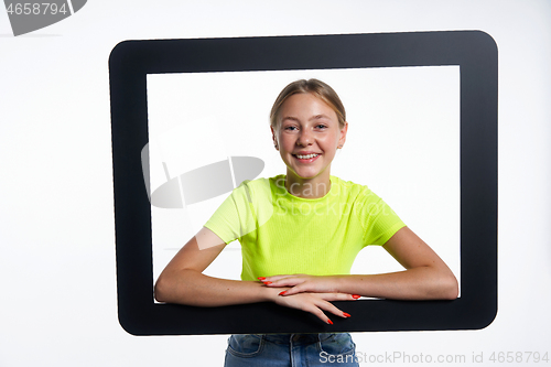 Image of Smiling teen girl looking through digital tablet frame