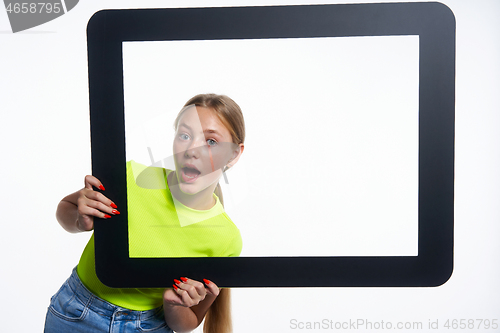 Image of Teen girl peeking through digital tablet frame