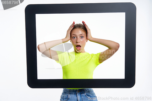 Image of Teen girl peeking through digital tablet frame