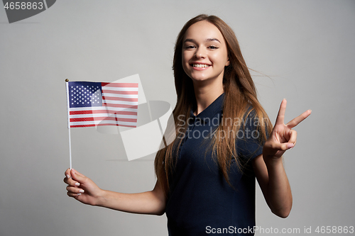 Image of Happy female holding United States of America flag and gesturing Victory