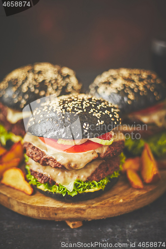 Image of Black double Burgers with Cheese. Cheeseburgers from Japan with black bun on dark background