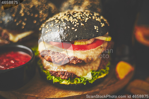 Image of Black double Burgers with Cheese. Cheeseburgers from Japan with black bun on dark background