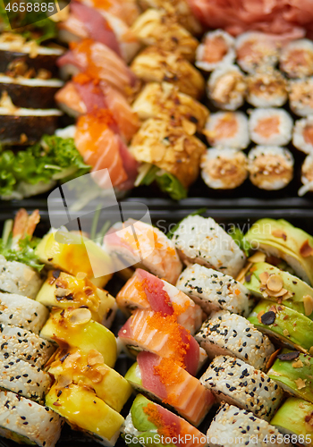 Image of Close up of Various sushi set in black plastic delivery box. Top view