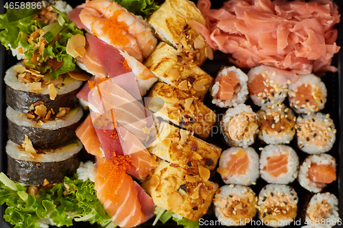 Image of Close up of Various sushi set in black plastic delivery box. Top view