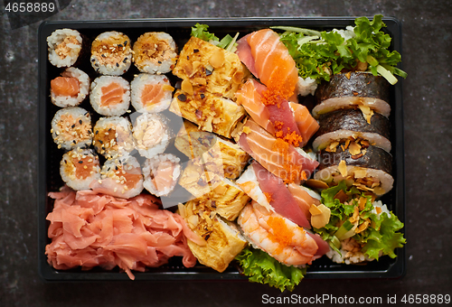 Image of Close up of Various sushi set in black plastic delivery box. Top view