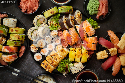 Image of Asian food fest. Menu sushi with nigiri, maki, uramaki on black plates. Various kinds of sushi